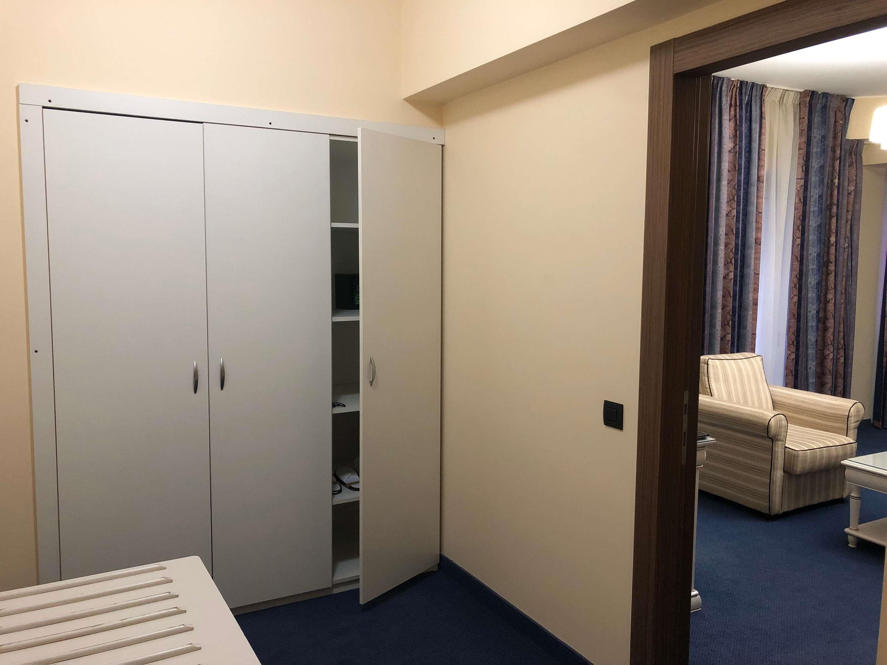 Una habitación con armario, una silla y una cama.