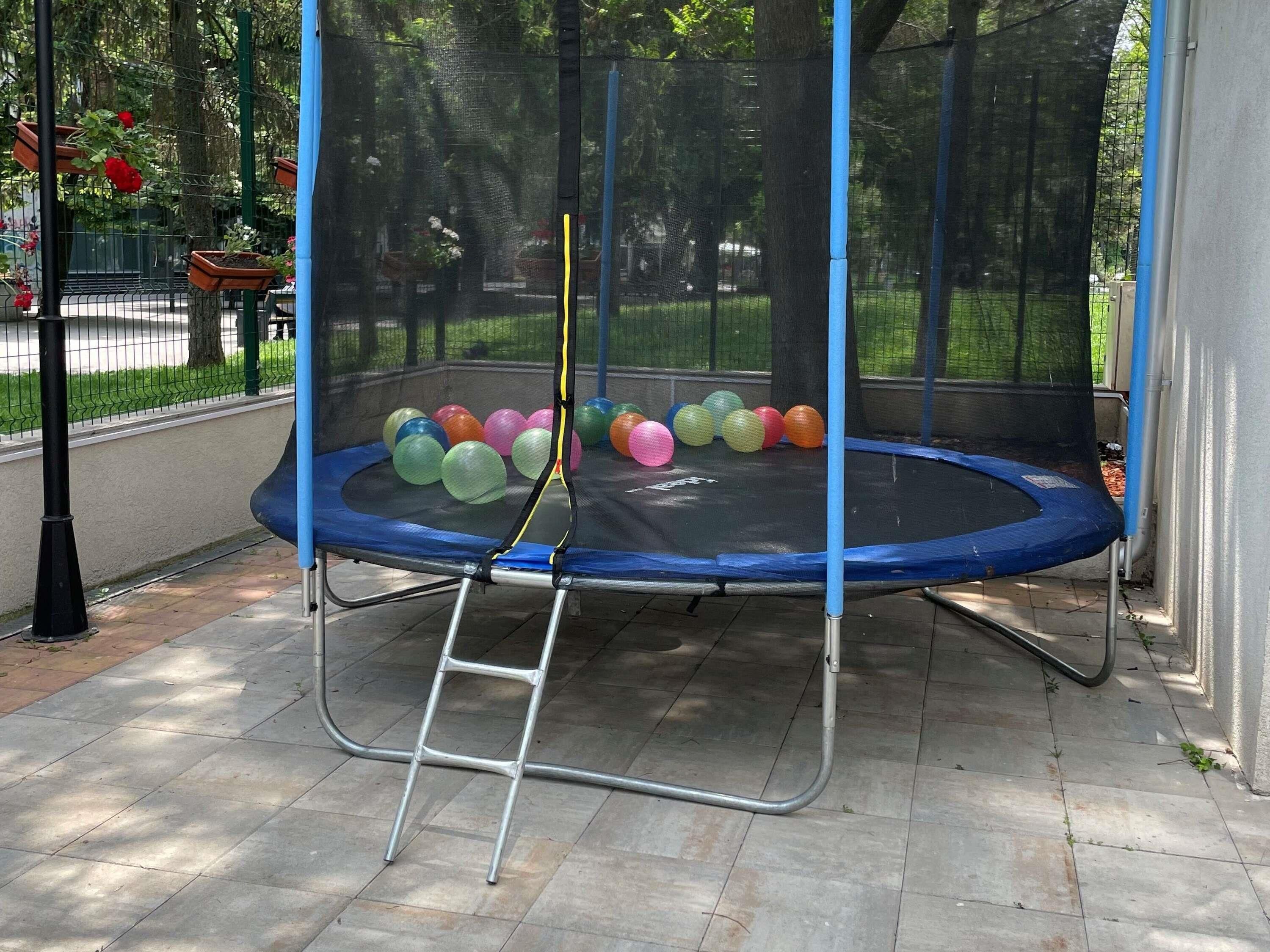 A trampoline with a safety net, surrounded by a paved area.