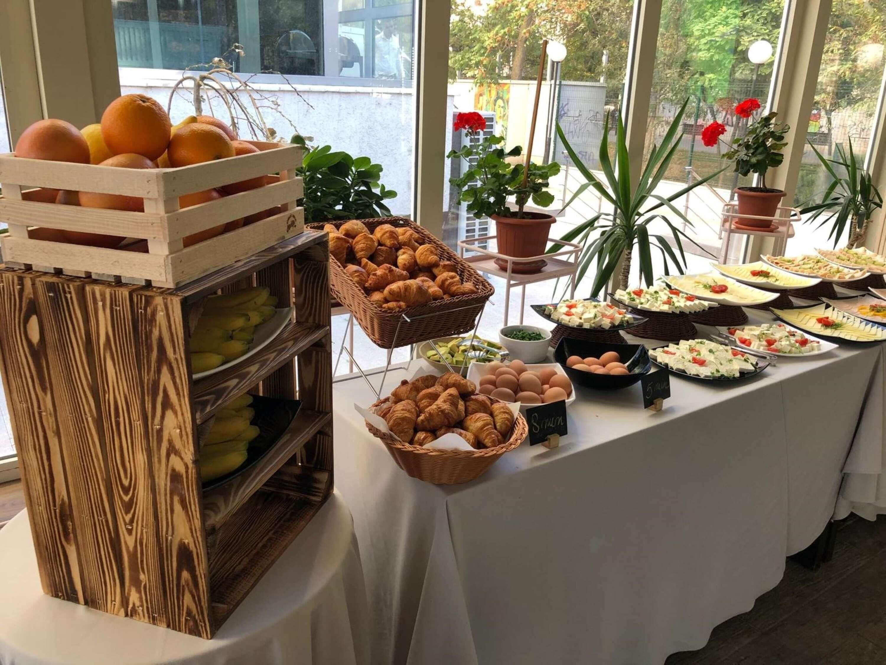 A buffet table with various food items and a wooden crate with fruits.
