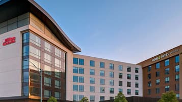 A modern hotel building with multiple floors, large windows, and a prominent Hilton Garden Inn sign.