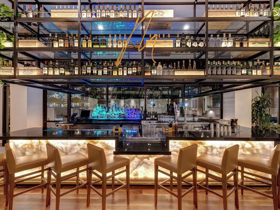 A bar with multiple shelves of liquor bottles, a bar counter, and bar stools.