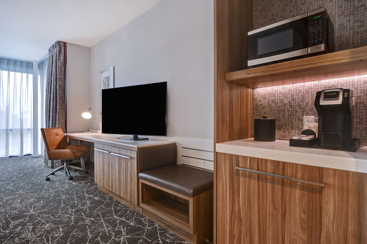 A hotel room with a desk, a television, a microwave, and a coffee maker.