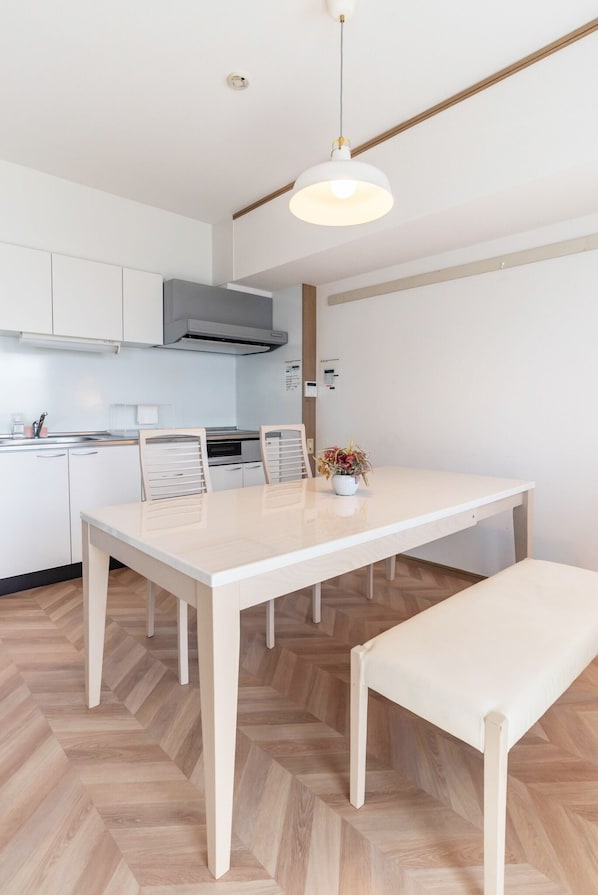 A modern kitchen with white cabinetry, a central island, and a pendant light.