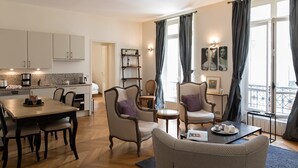A modern living room with a dining area, a kitchen, and a balcony with curtains. - Monceau Chic I Charming 1 Bed Apt in the 8th (Paris)