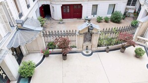 A courtyard with a red door, potted plants, and a black wrought iron fence. - Monceau Chic I Charming 1 Bed Apt in the 8th (Paris)
