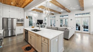 A spacious kitchen with a central island, stainless steel appliances, and a wooden ceiling.