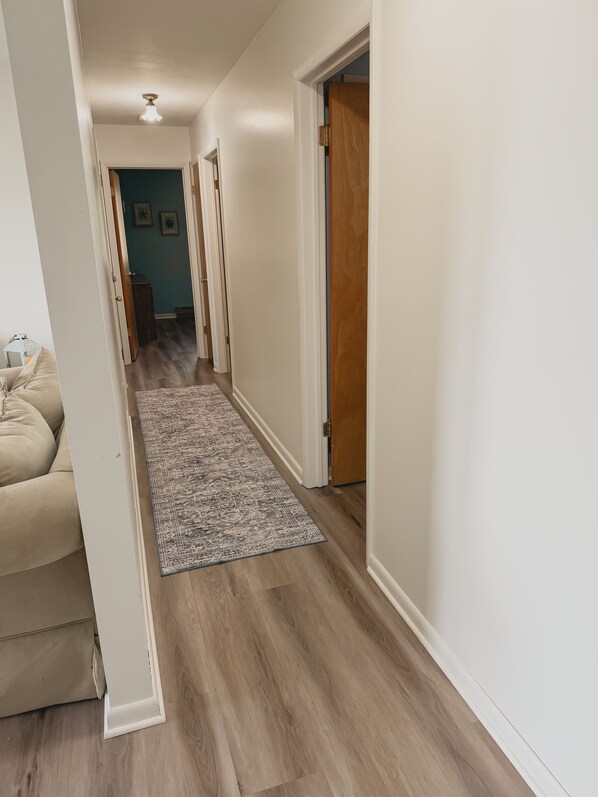 A hallway with a wooden floor, a beige sofa, and a patterned rug.