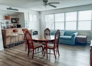 Un comedor con una mesa y sillas de madera, un sofá azul y un ventilador de techo.