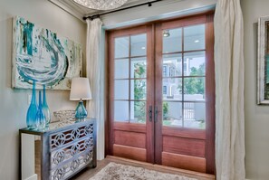A room with a wooden door, a decorative console table, and a painting on the wall.