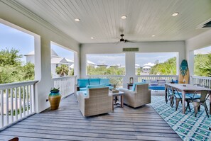 A covered outdoor area with wicker furniture, a table, and chairs.