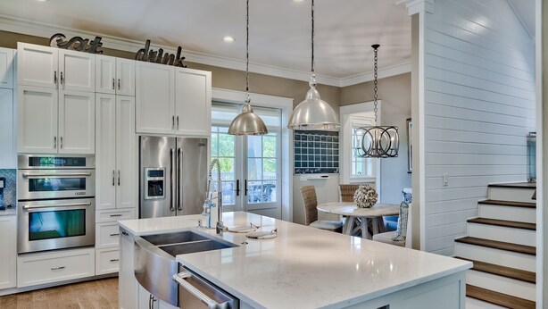 A modern kitchen with white cabinetry, stainless steel appliances, and pendant lighting.
