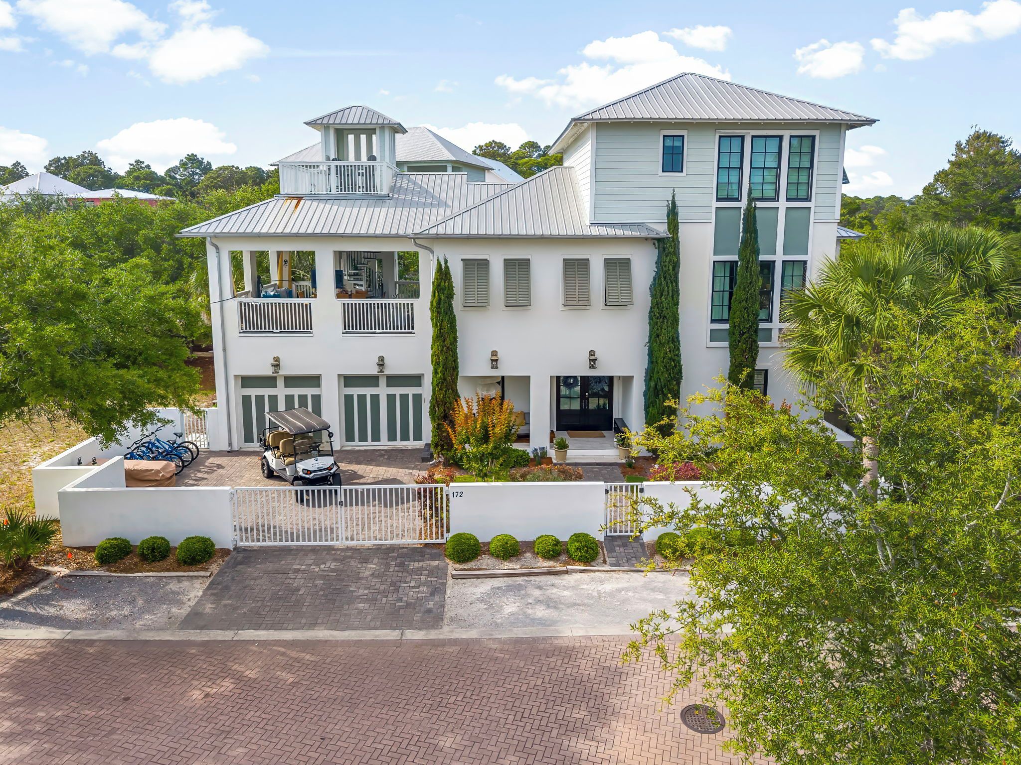 A large, multi-story house with a prominent balcony, a garage, and a well-maintained garden.