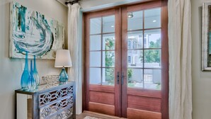 A room with a wooden door, a decorative console table, and a painting on the wall.