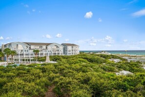 Un grand hôtel en bord de mer, doté de nombreuses chambres, d’une piscine et d’un espace extérieur aménagé avec des sièges.