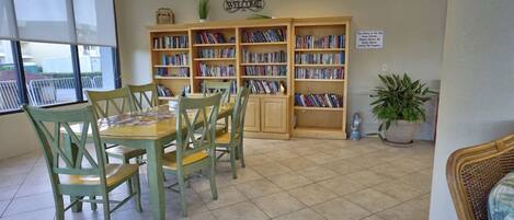 Una biblioteca con una mesa, sillas, estanterías y un letrero de bienvenida.