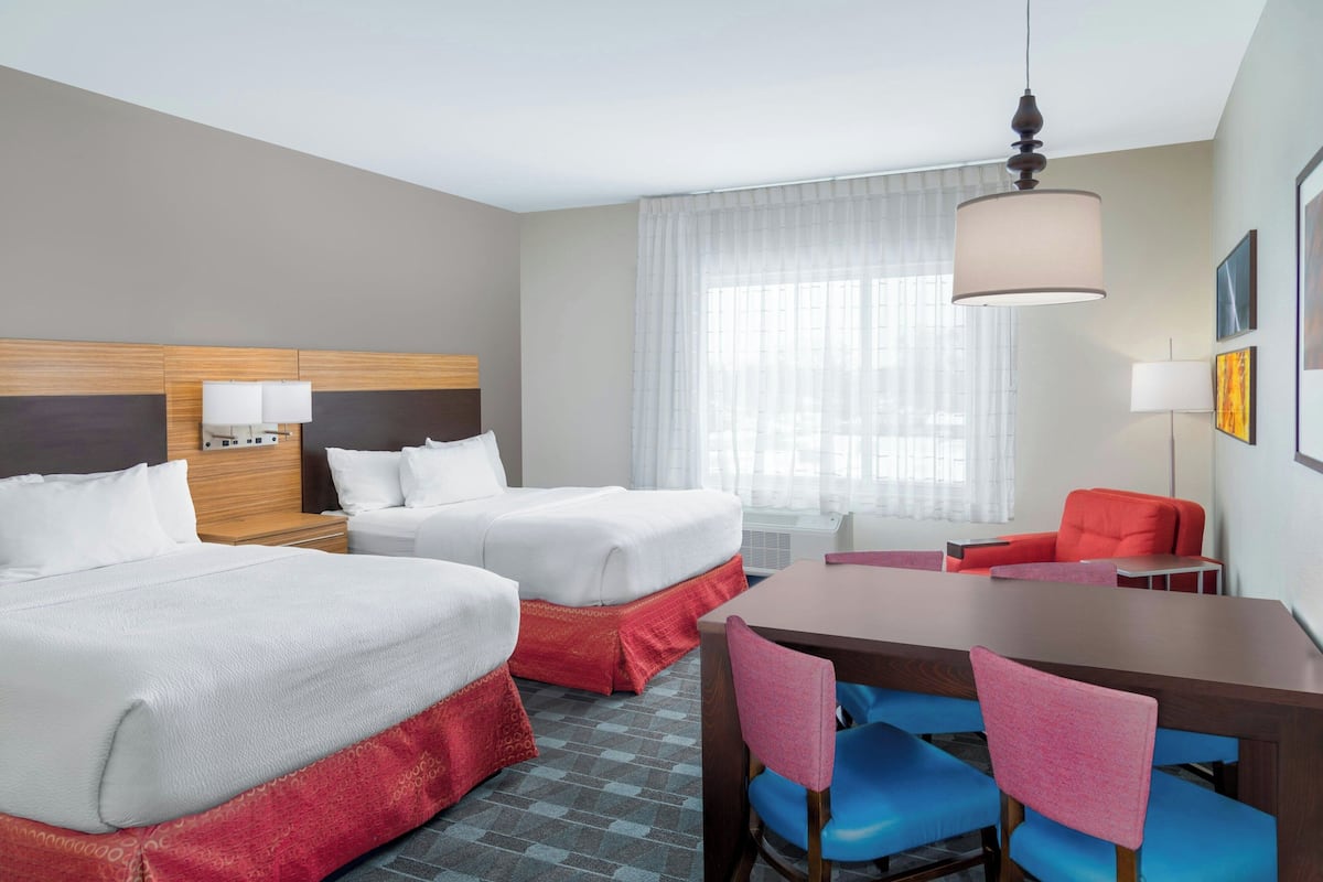 Une chambre d’hôtel avec deux lits, une table à manger et des chaises.