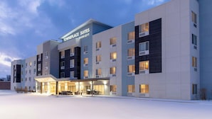 A modern hotel with a flat roof, multiple floors, and a covered entrance area with seating.