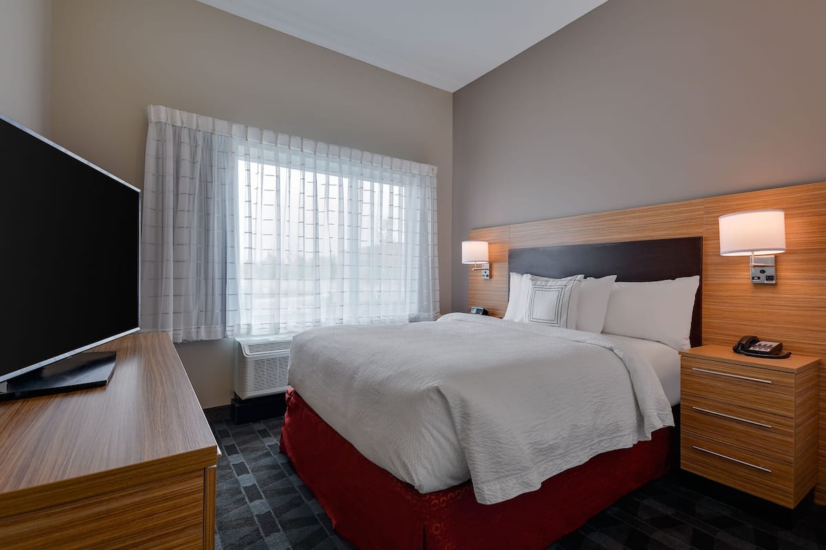 Une chambre d’hôtel équipée d’un lit, d’une télévision, d’une table de chevet, d’une lampe et d’un téléphone.