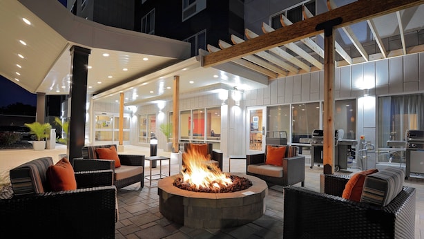 An outdoor seating area with wicker furniture and a central fire feature.