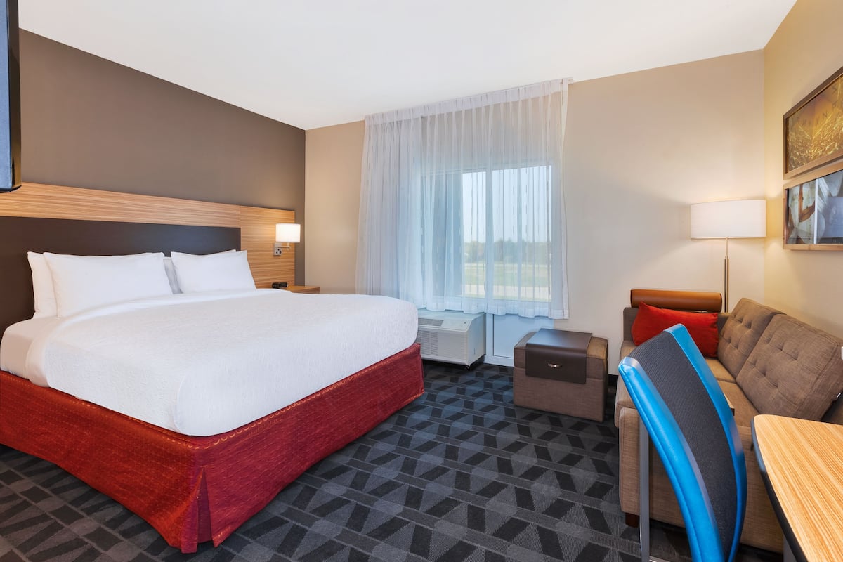 Una habitación de hotel con una cama grande, un sofá, un escritorio y una silla.