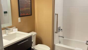 A modern bathroom with a white sink, toilet, and bathtub. There is a framed quote on the wall and a towel rack by the bathtub.