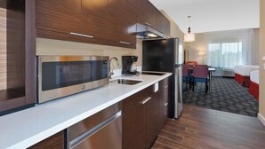 A modern kitchen with stainless steel appliances, a coffee maker, and a dining area with a table and chairs.