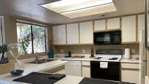 Una cocina moderna con armarios blancos, un microondas negro, una estufa y un lavavajillas.