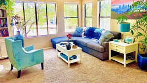 Una sala de estar con un sofá, un sillón, una mesita de centro, una lámpara y una estantería.