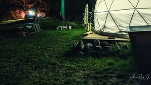A dome tent set up in a grassy area with a starry night sky and a visible Milky Way. - ComfyDome Forest-Side Glamping (Jefferson)