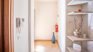 A hallway with a telephone, a vase, and a fire extinguisher.