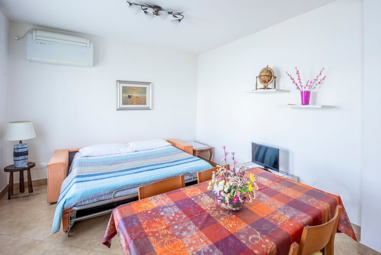 A room with two beds, a table with a floral centerpiece, a globe, and a framed picture on the wall.