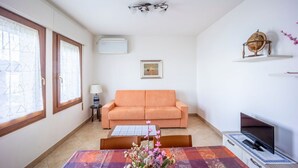 A living room with a sofa, a table with a vase, a globe on a shelf, and a TV on a stand.