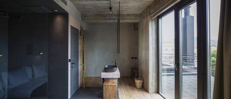 A modern bathroom with a large window, a wooden bench, and a sink.