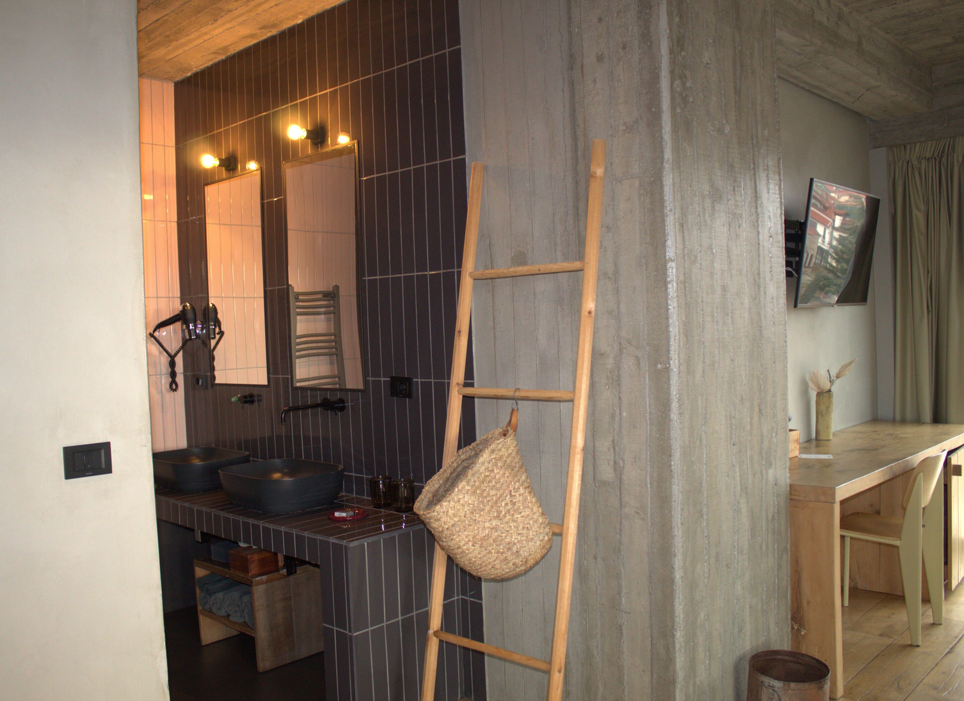 Un baño con un espejo grande, dos lavamanos y una escalera de madera apoyada en la pared.