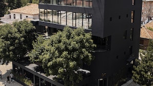 A modern multi-story building with a rooftop garden, large windows, and a flat roof. - In Gallery Spa & Hotel (Korçë)
