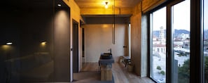 A modern interior with a minimalist design, featuring a wooden ceiling, a large window with a view of a cityscape, and a built-in sink on a wooden platform. - In Gallery Spa & Hotel (Korçë)