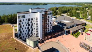 A modern multi-story hotel with a rooftop pool and a view of a lake. - Hotelli Kuohu (Kangasala)