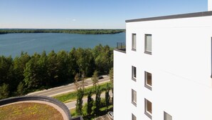 A modern building with multiple windows overlooking a lake and forested area. - Hotelli Kuohu (Kangasala)