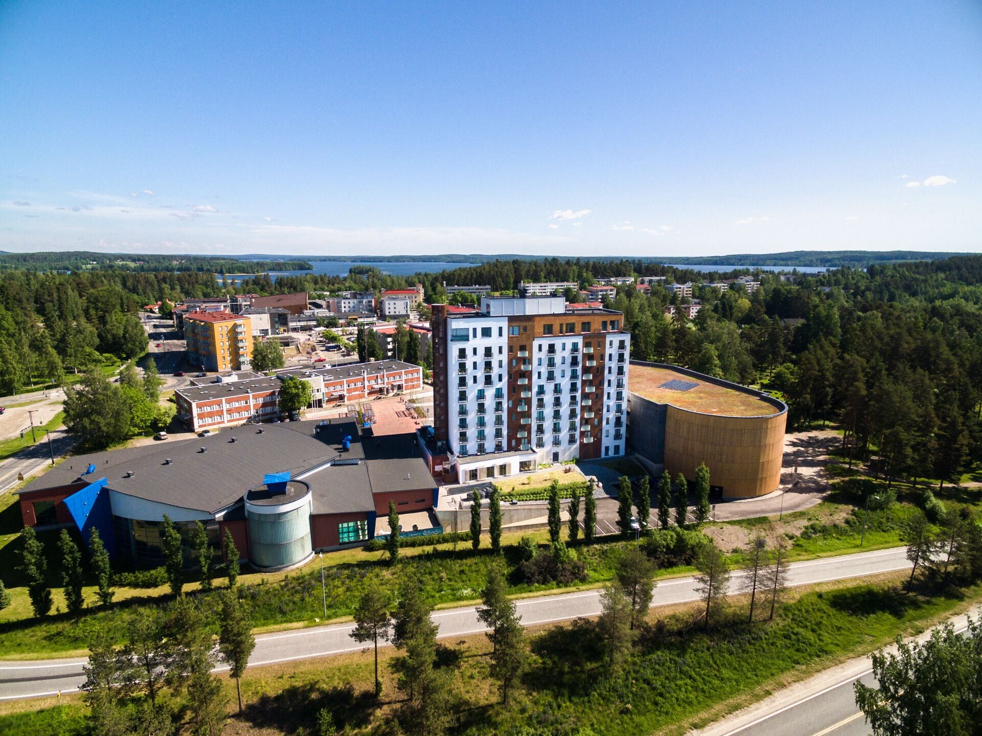 Un ensemble immobilier moderne comprenant plusieurs immeubles d’appartements, une grande structure cylindrique et un espace de stationnement.
