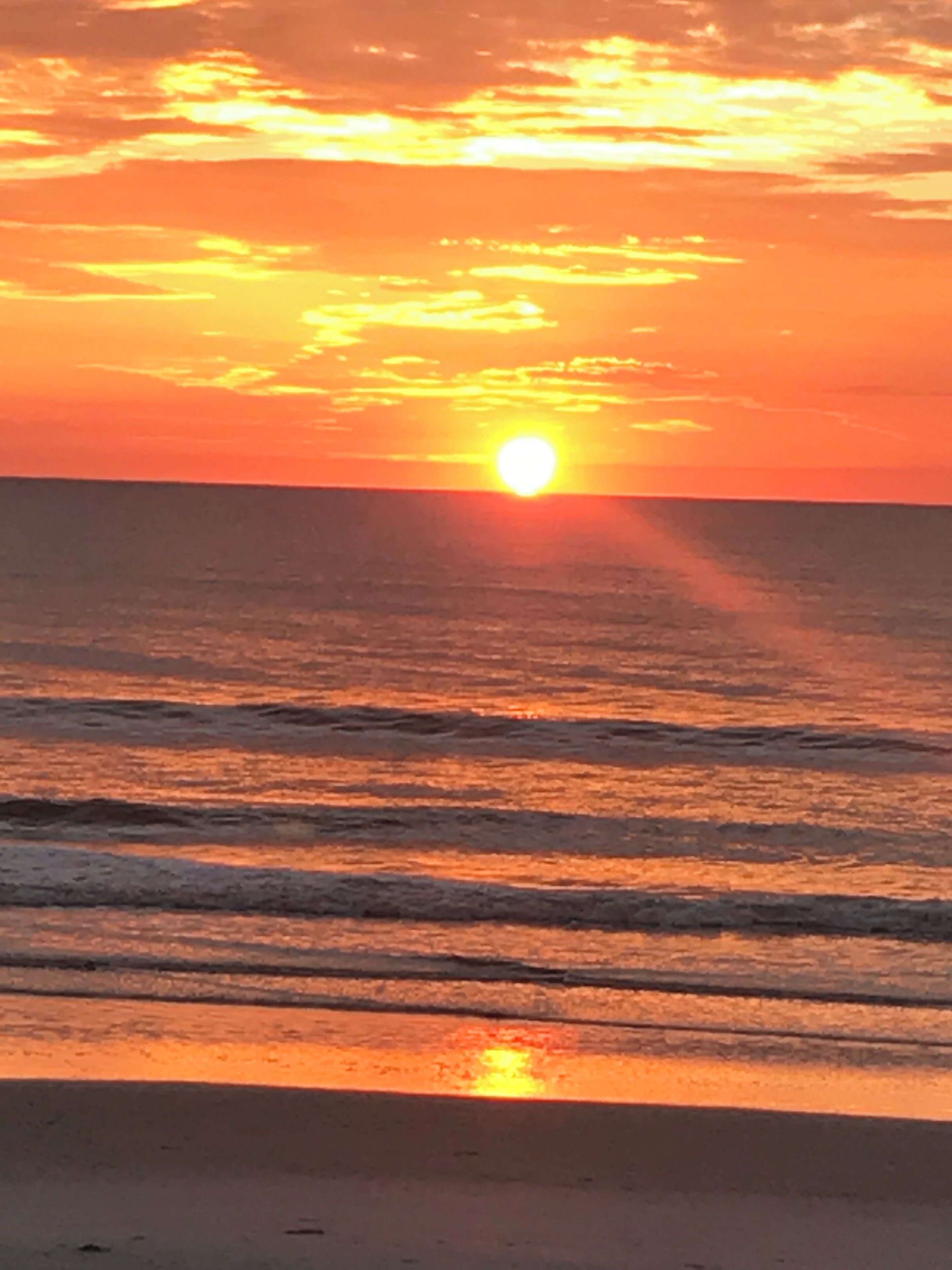 A sunset over the ocean with the sun visible near the horizon.