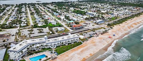 A coastal residential area with a beachfront hotel featuring a swimming pool and a beach view.