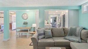 Un salon avec un canapé beige, une table basse en bois et un coin repas comprenant une table et des chaises.