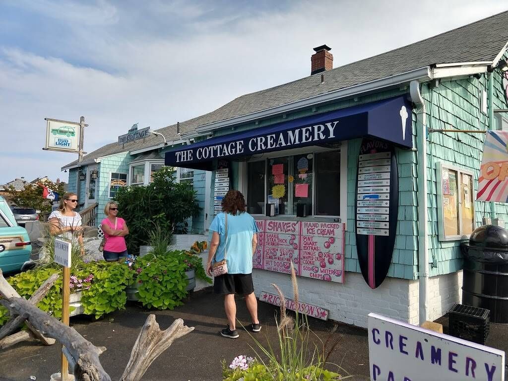 Une boutique de crème glacée dont l’enseigne indique « The Cottage Creamery » et qui propose un tableau affichant différentes sortes de crème glacée.