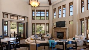 A spacious living room with a fireplace, large windows, and a television. - Abode at Alpine Penthouse, ski-in/ski-out, sauna, pool & gym (Park City)