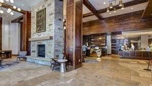 A lobby with a stone fireplace, wooden beams, and a reception desk. - Abode at Alpine Penthouse, ski-in/ski-out, sauna, pool & gym (Park City)