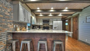A kitchen with a central island, bar stools, and wooden flooring.