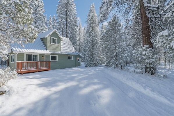 Eine Holzhütte mit Metalldach, einer Veranda und umgeben von schneebedeckten Bäumen.