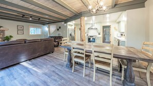 A spacious living area with a wooden dining table, a sofa, and a chandelier. - The Sparrow’s Nest ~ Cozy Charm + Fire Pit Fun (Shaver Lake)