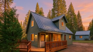 A two-story cabin with a porch, surrounded by tall trees and a dirt driveway. - The Sparrow’s Nest ~ Cozy Charm + Fire Pit Fun (Shaver Lake)