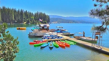 A lakeside dock with colorful kayaks and a small boat rental area.